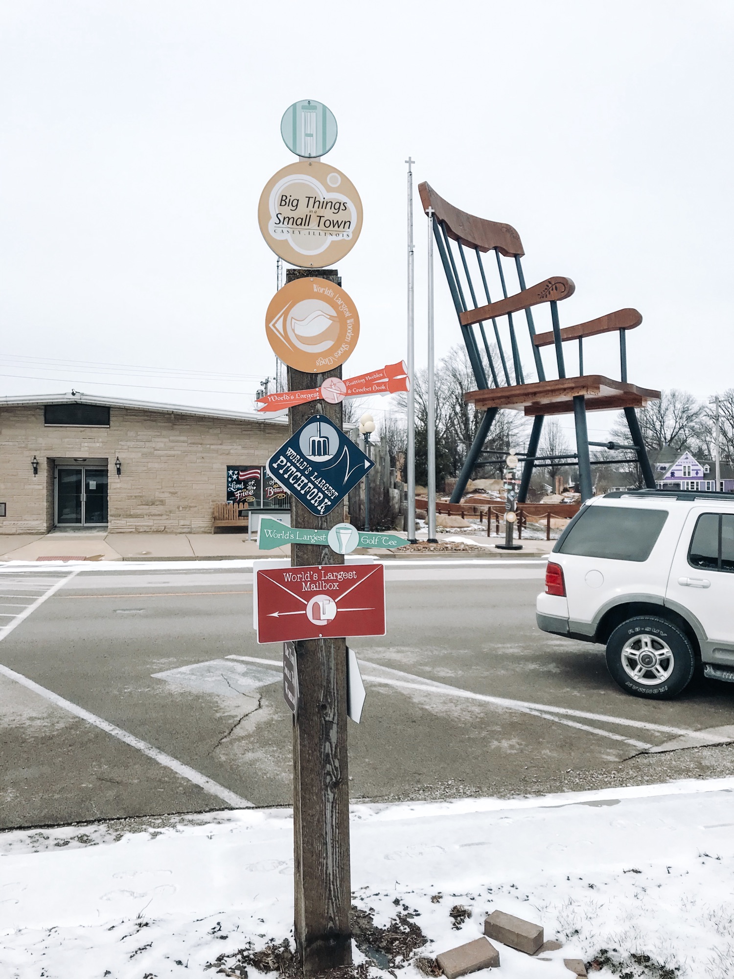 The World's Largest Rocking Chair is in the background with a post full of signs pointing to various big thing and World's Largest things throughout the town.