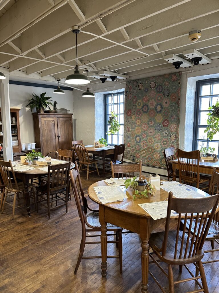 dining area at Cream and Crepe restaurant with vintage furniture and an antique quilt on the wall