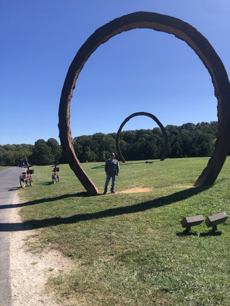 Dominic standing under one of the large circle art sculpture.