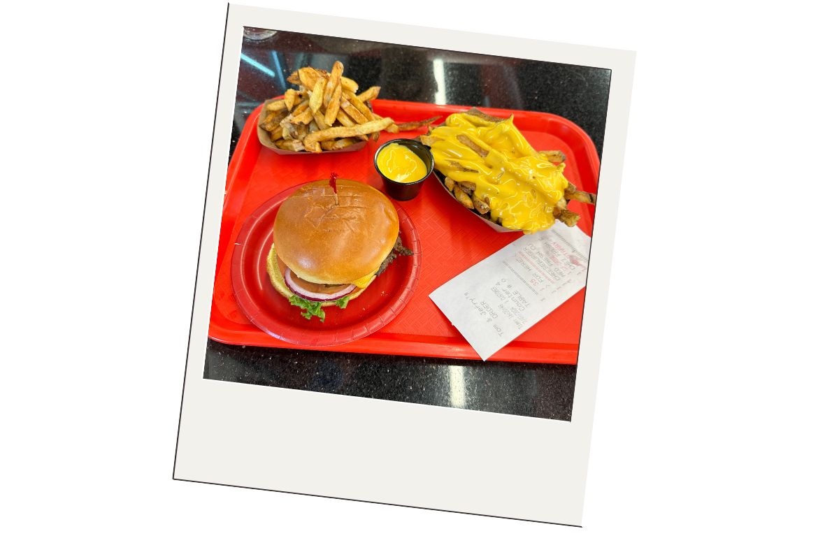 Polaroid style picture: Red tray with a burger on a red plate, fries covered with cheese and another order of fries with a cup of cheese.