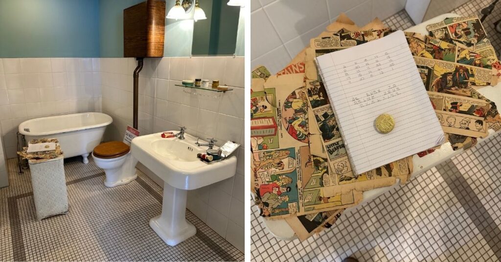 A Christmas Story house- bathroom. The image shows a vintage-style bathroom with a pedestal sink, clawfoot bathtub, and a toilet with a wooden seat and an elevated wooden tank. The tiled floor and walls give the room a clean, classic look. On a small hamper next to the bathtub, there are old comic book pages and a notepad with handwriting, along with a golden coin placed on top. The close-up view highlights the comic strips and the handwritten note, which appears to be a code or puzzle, adding a quirky, nostalgic element to the scene.