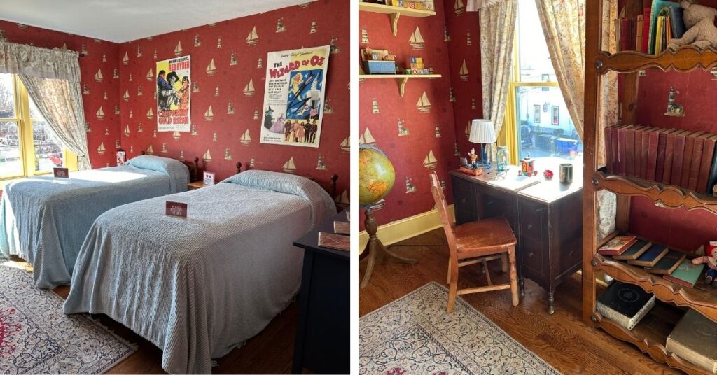 A Christmas Story house- bedroom. The image on the left shows two twin beds with matching blue bedspreads and a poster hanging over each bed. There is red wallpaper with sailboats all over the walls. There is also a yellow window with curtains. 
The image on the right shows a desk and chair and a large bookcase. The desk has some trinkets and a notebook on it. It is sitting in front of a yellow window with curtains. There is a rug on the floor.