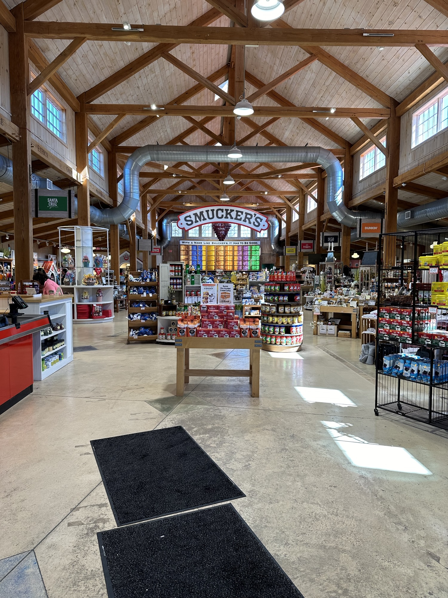 Inside the Smucker's store. There is a large "Smucker's" sign and a lot of merchandise and a colorful wall of jars on the far back wall.